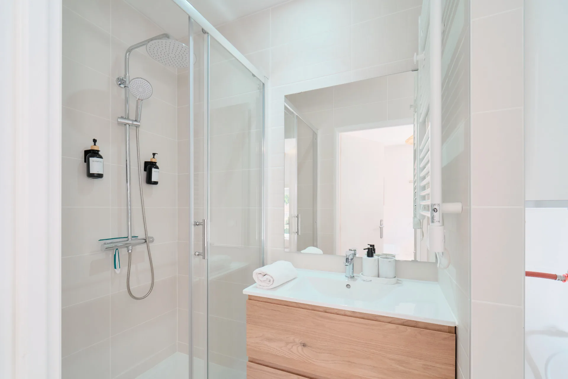 Salle d’eau privative avec vasque en bois, douche vitrée et ciel de pluie.