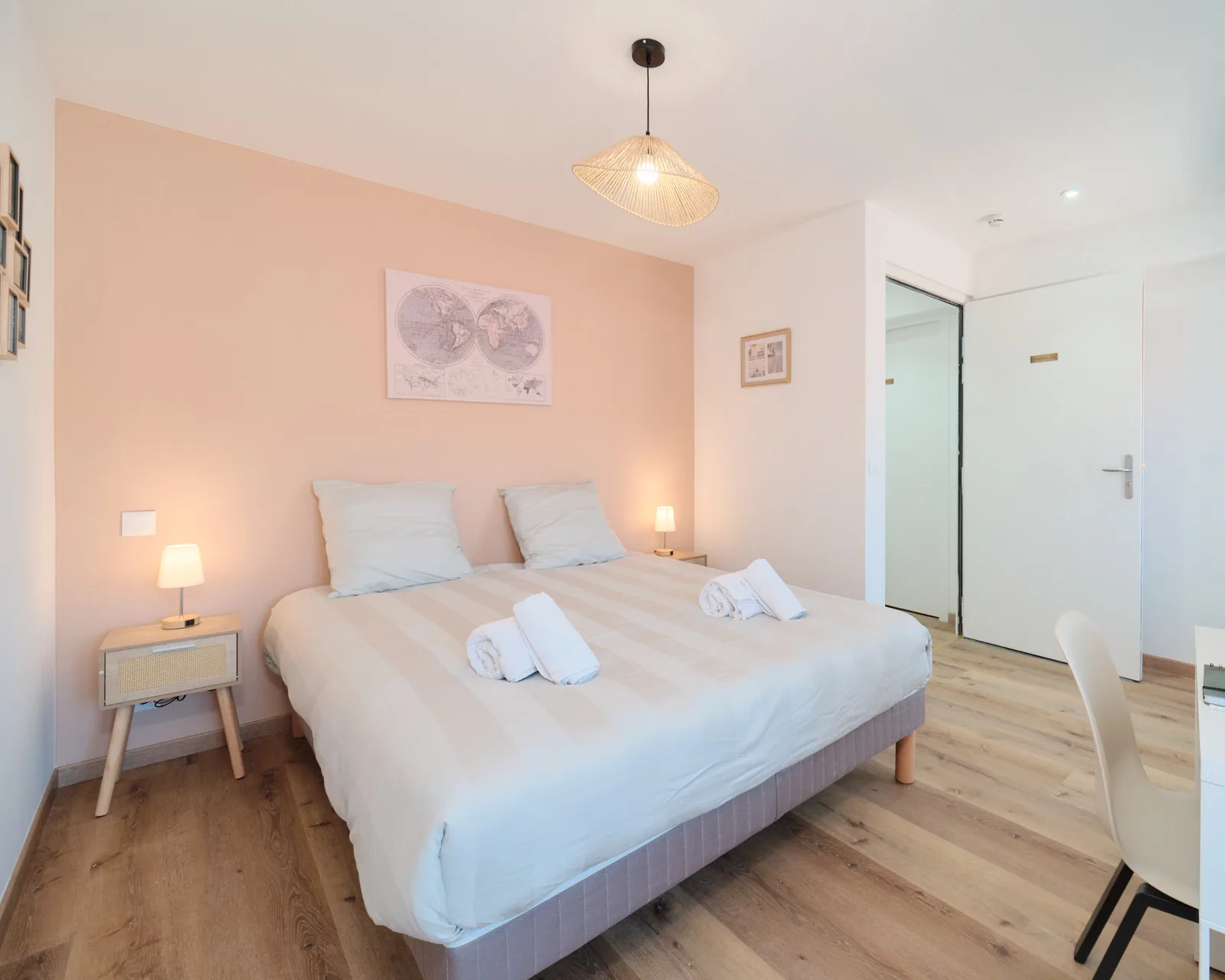 Chambre double lumineuse aux tons poudrés, avec lit préparé, lampes de chevet et bureau.
