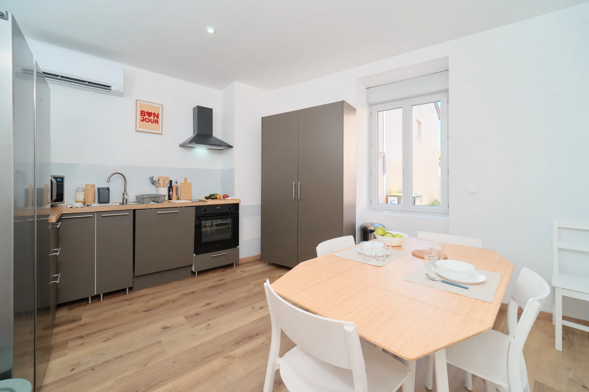 Cuisine partagée équipée avec four, plaque de cuisson, micro-ondes et table à manger.